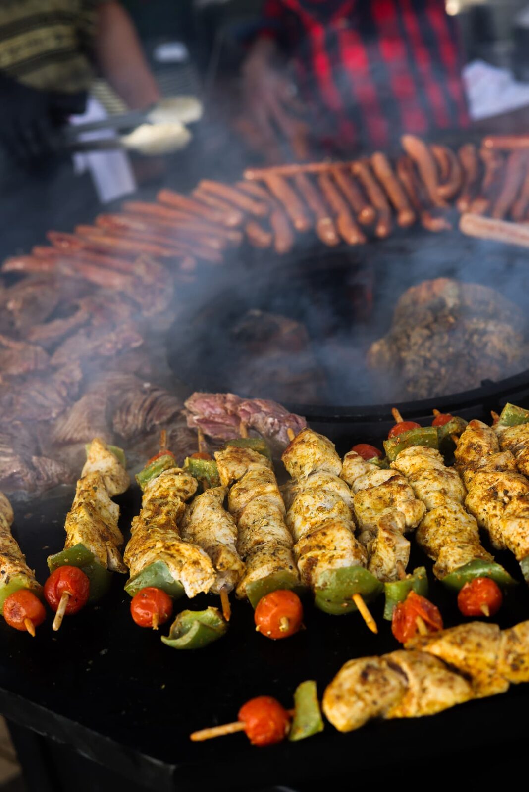 Brochettes de volaille et saucisses en cuisson sur la couronne du brasero